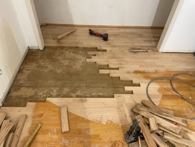 A wooden floor is being repaired in a room.