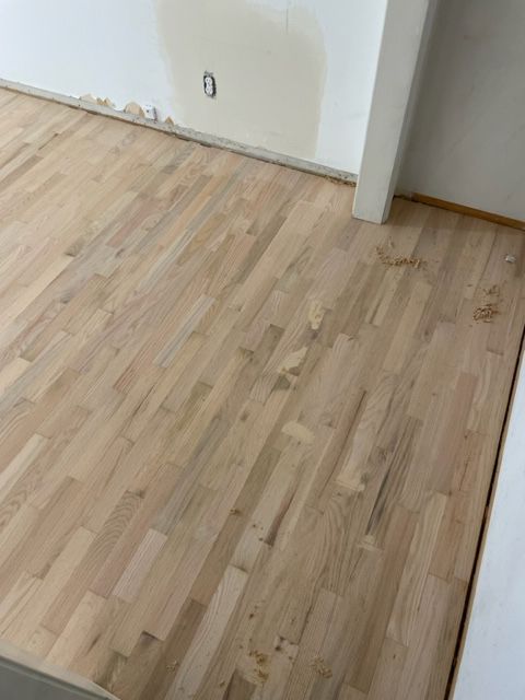 A wooden floor in a room with a white wall.