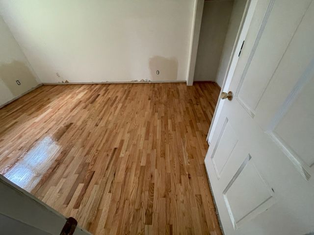 A bedroom with hardwood floors and a white door.