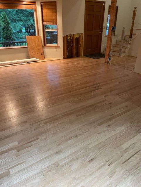 A living room with a wooden floor and a window.