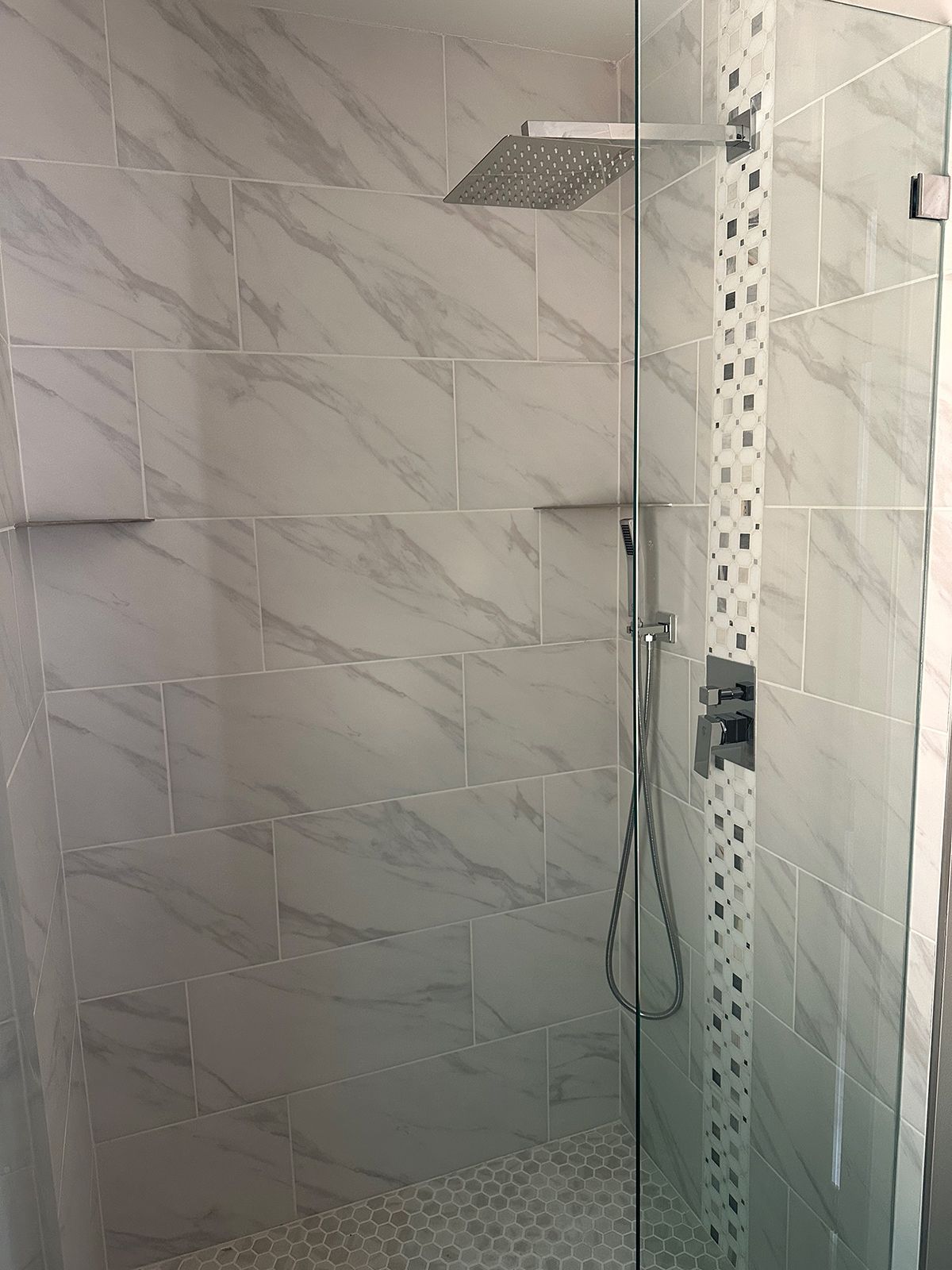 A shower with a glass door and a shower head.