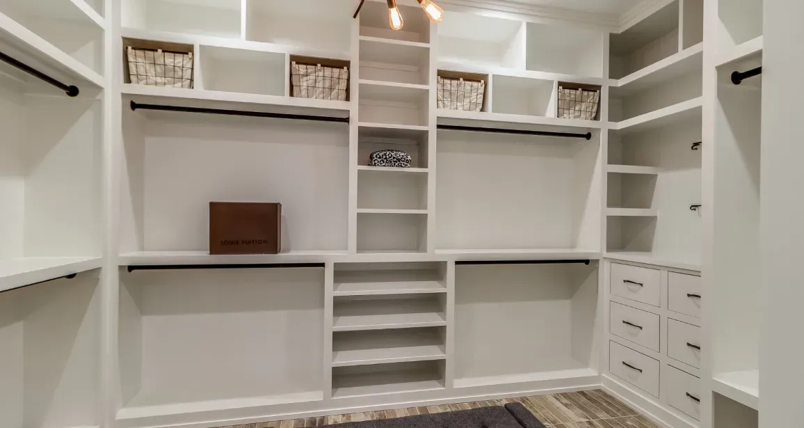 White walk-in closet with shelves, drawers, and hanging rods; storage space.