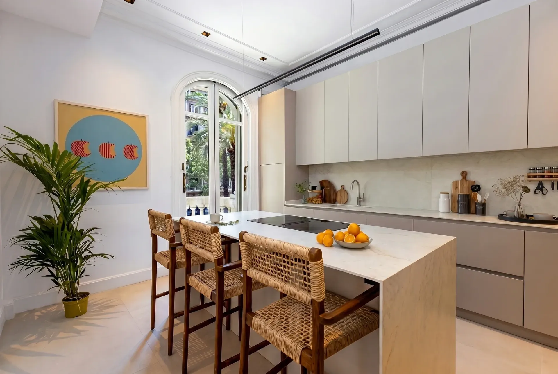 Render inmobiliario de cocina moderna con isla de mármol, taburetes de fibra y ventanal arqueado