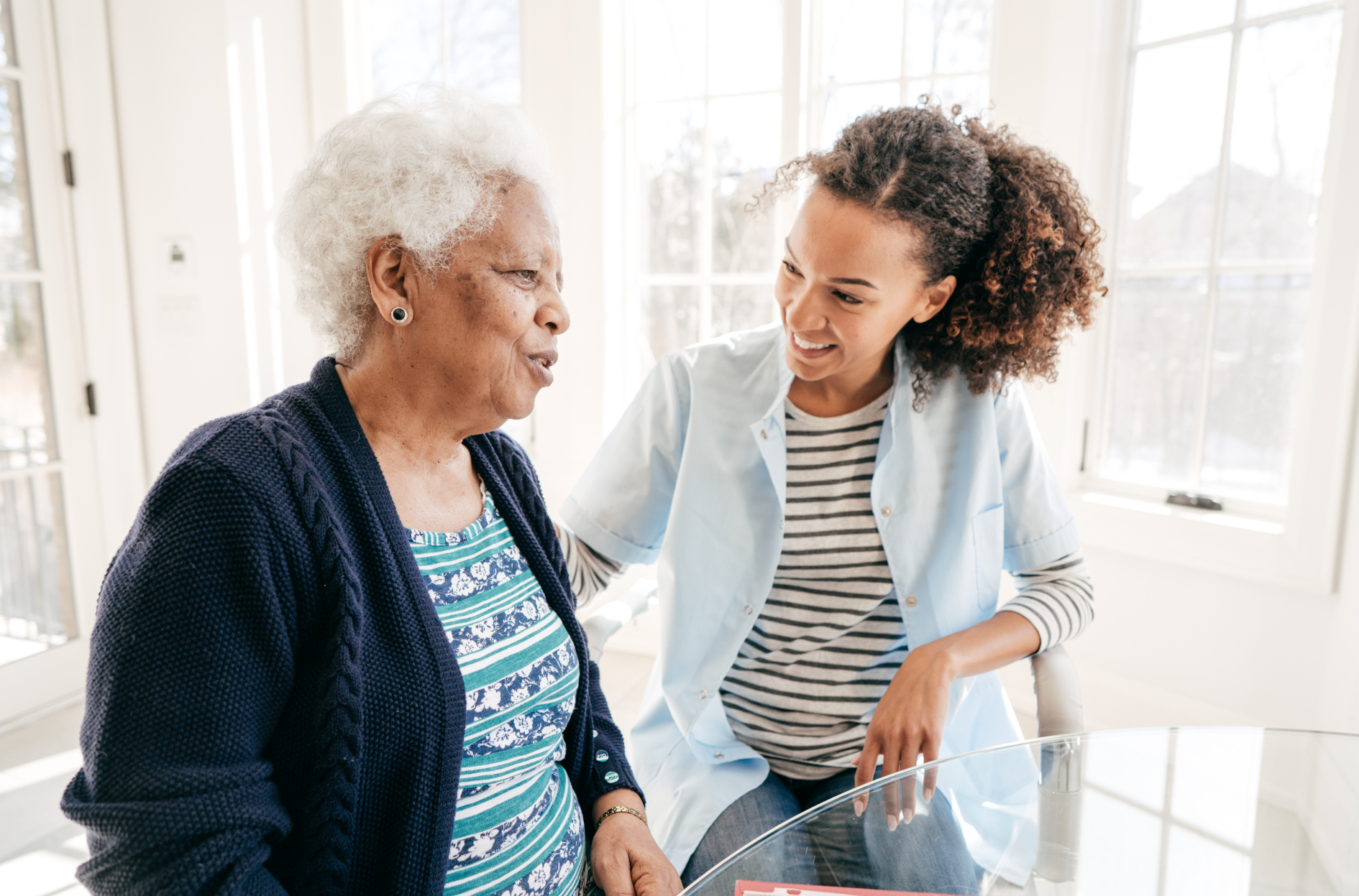 A nurse is talking to an elderly woman in a living room.