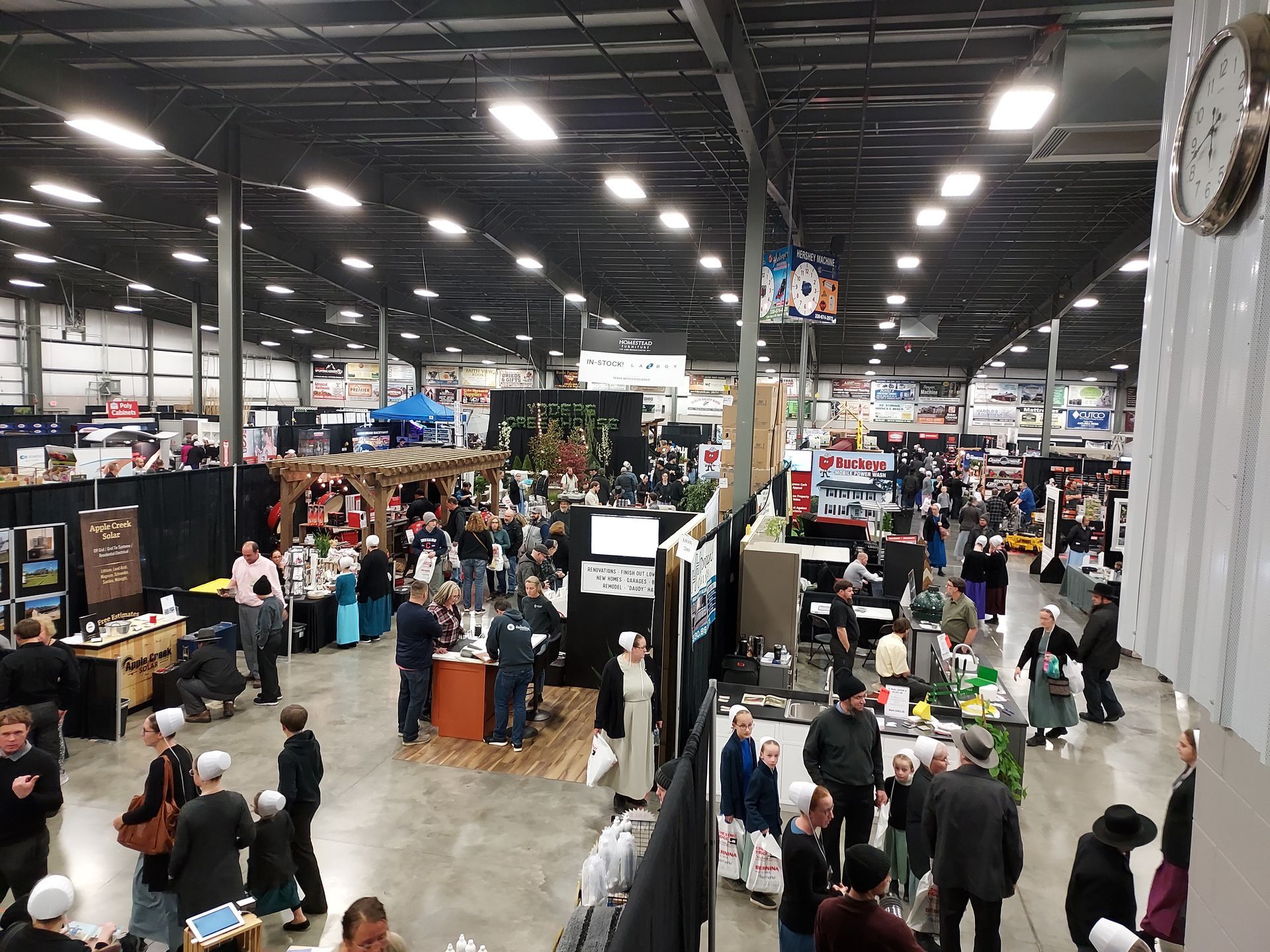 Large indoor event with many booths and people; overhead view.
