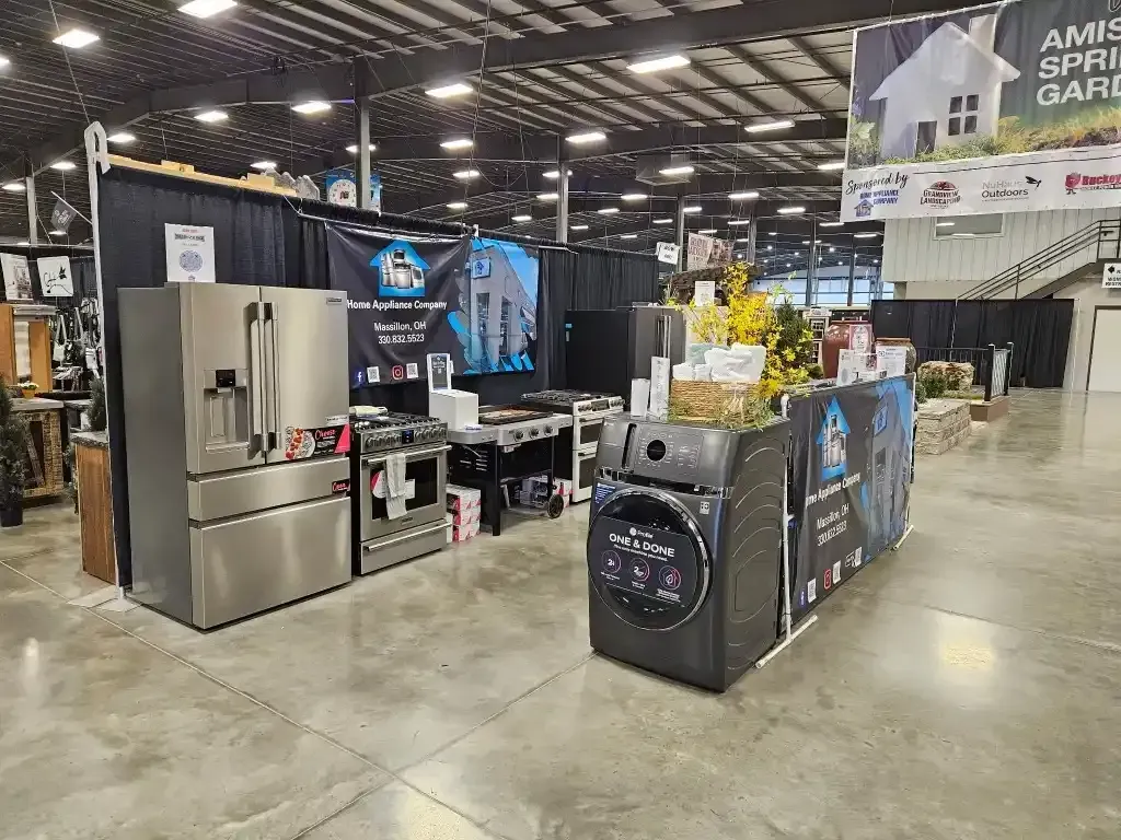 Appliances on display at a trade show booth, including a refrigerator, stove, and washing machine.