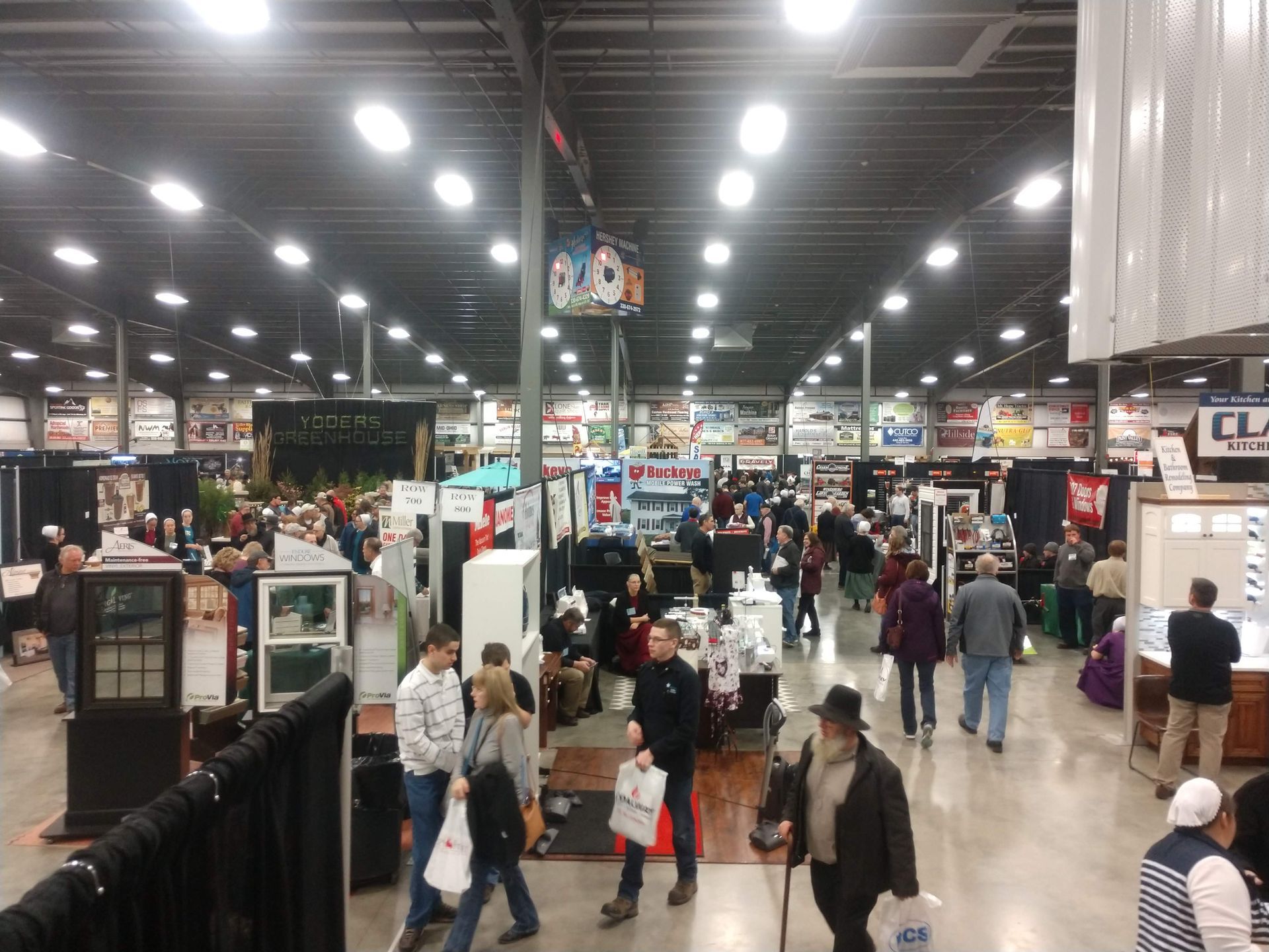Large indoor event with many booths and people walking around.