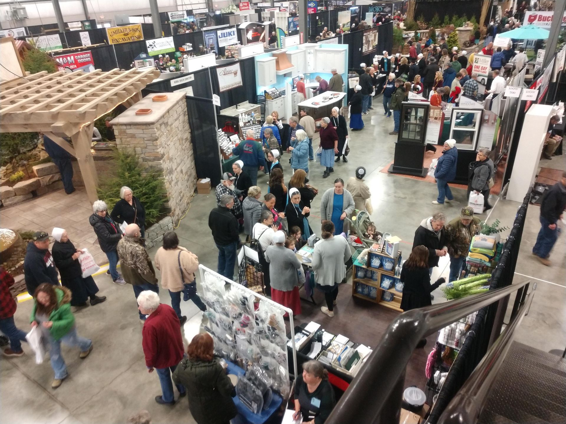 Crowd at a trade show with booths. People browse products in an indoor space.