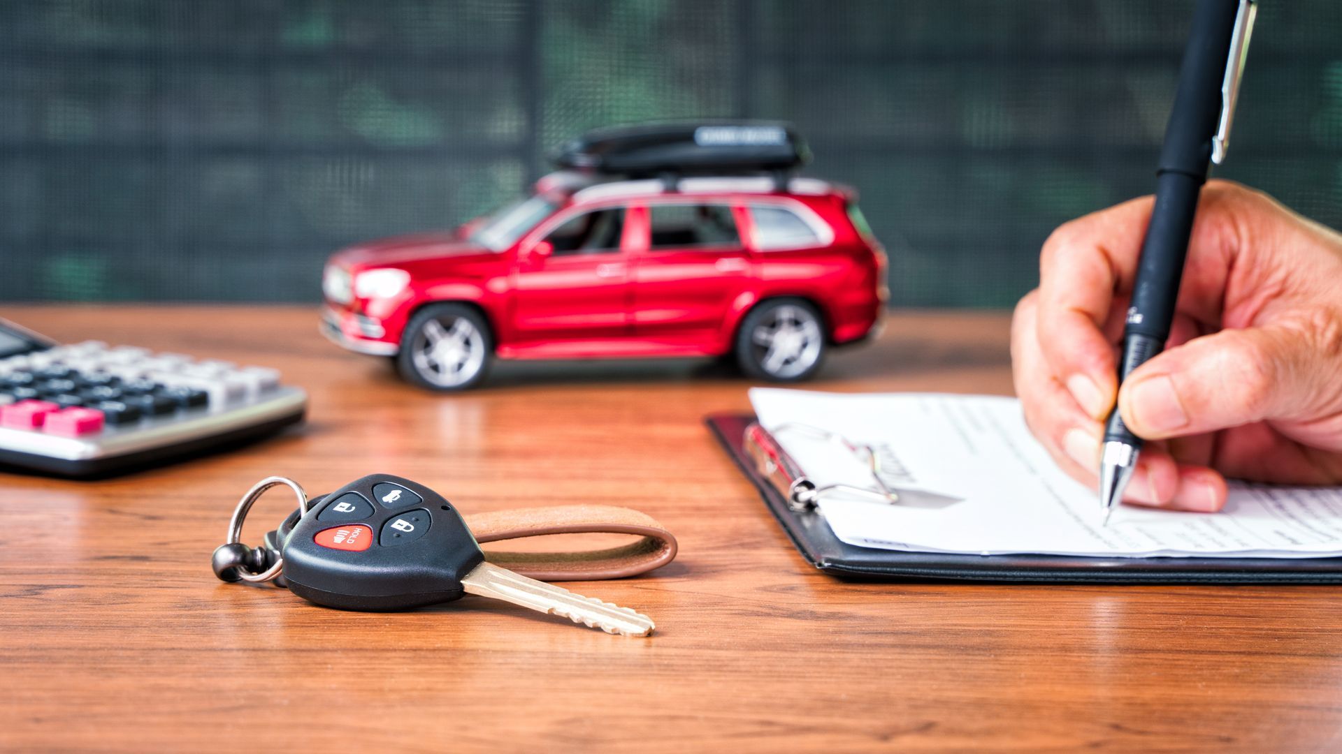 Car key on table with a man signing on leasing.
