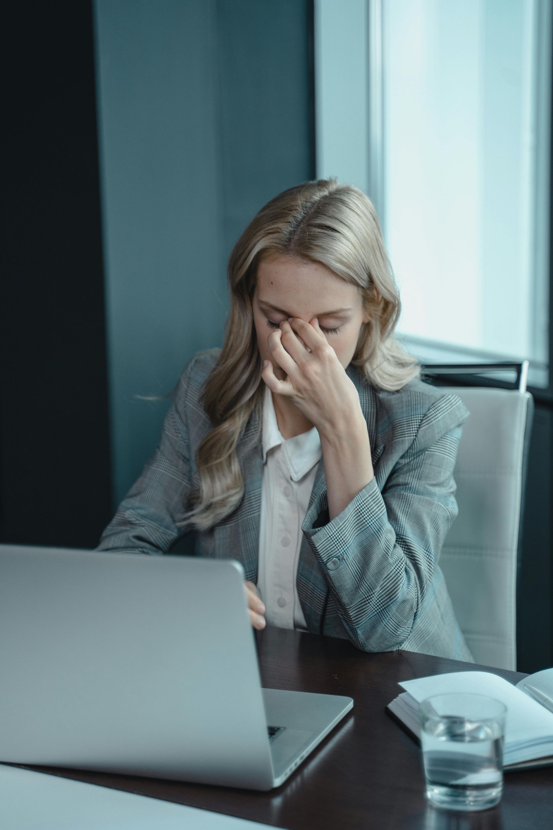 Image of a stressed out woman holding her face sitting at a desk