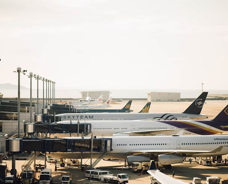 A row of planes are parked at an airport.