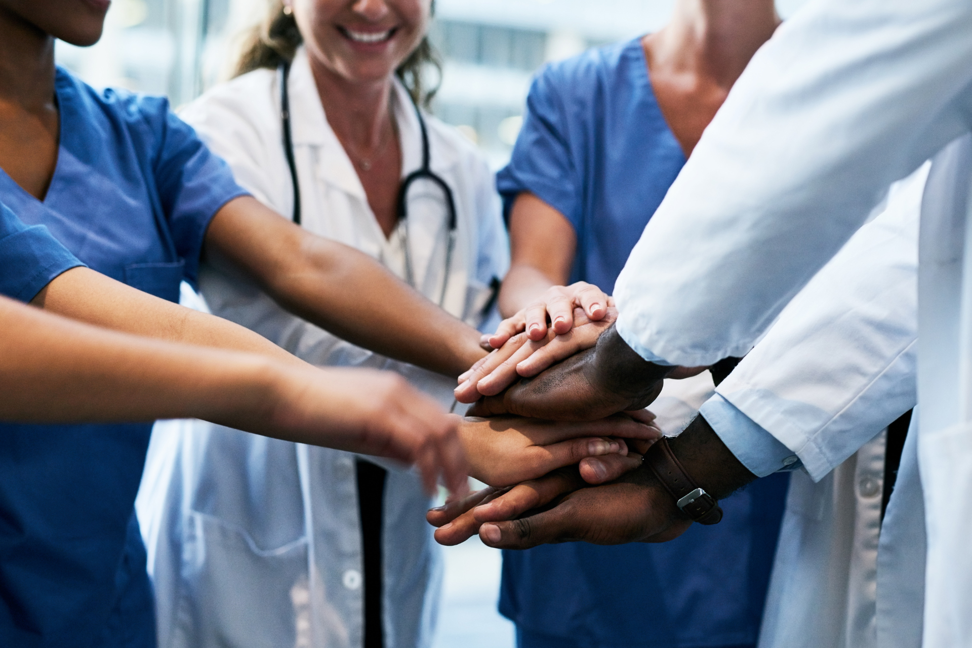 A group of doctors and nurses are putting their hands together.