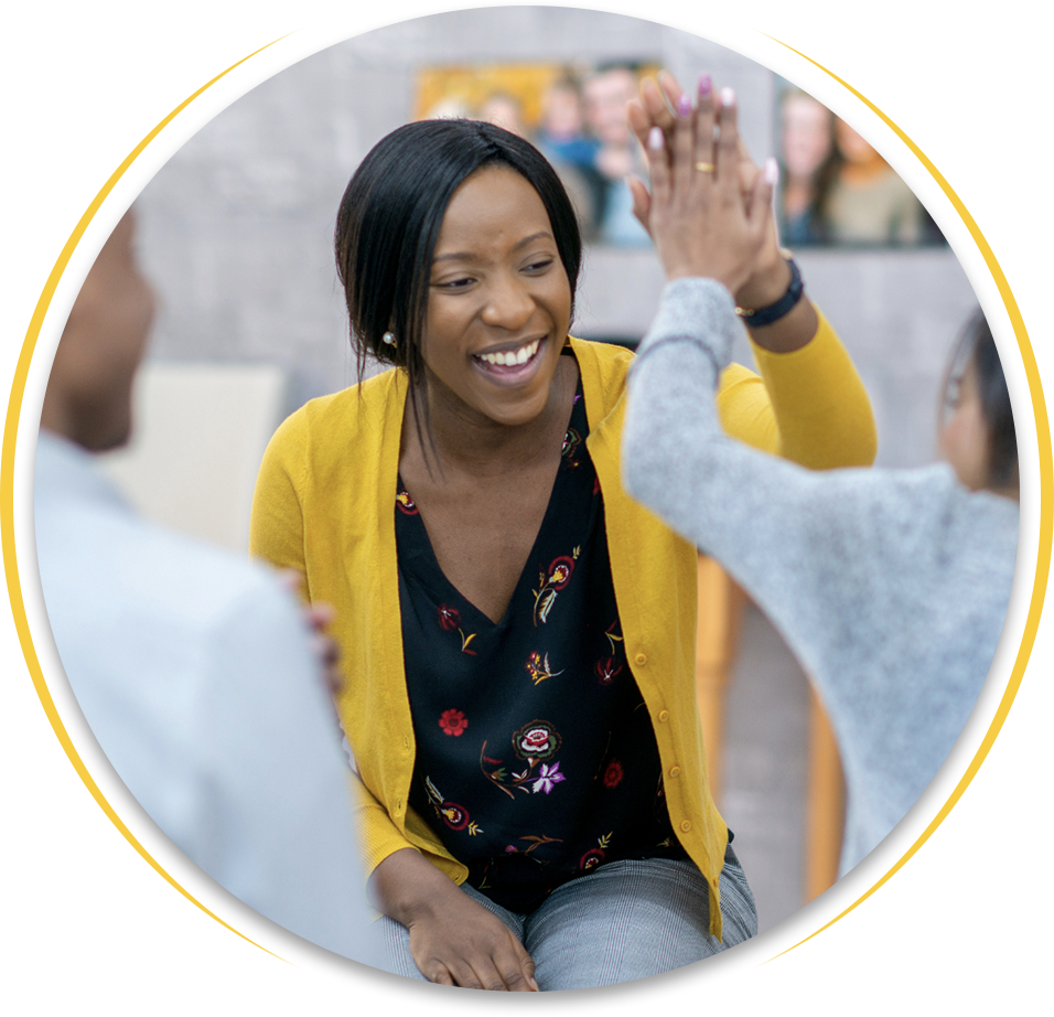 A woman in a yellow cardigan is giving a high five to another woman.