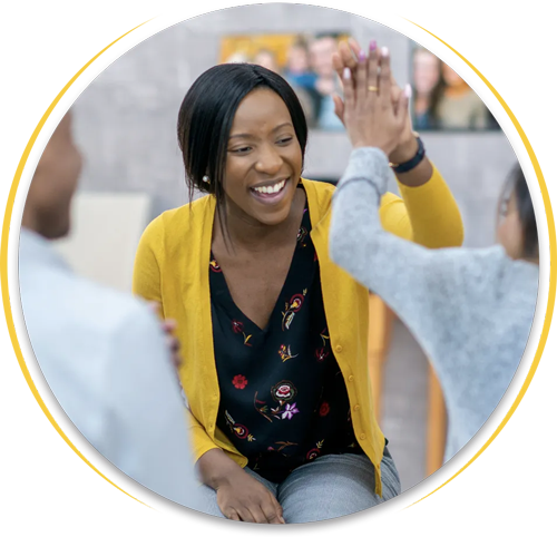 A woman in a yellow cardigan is giving a high five to another woman.