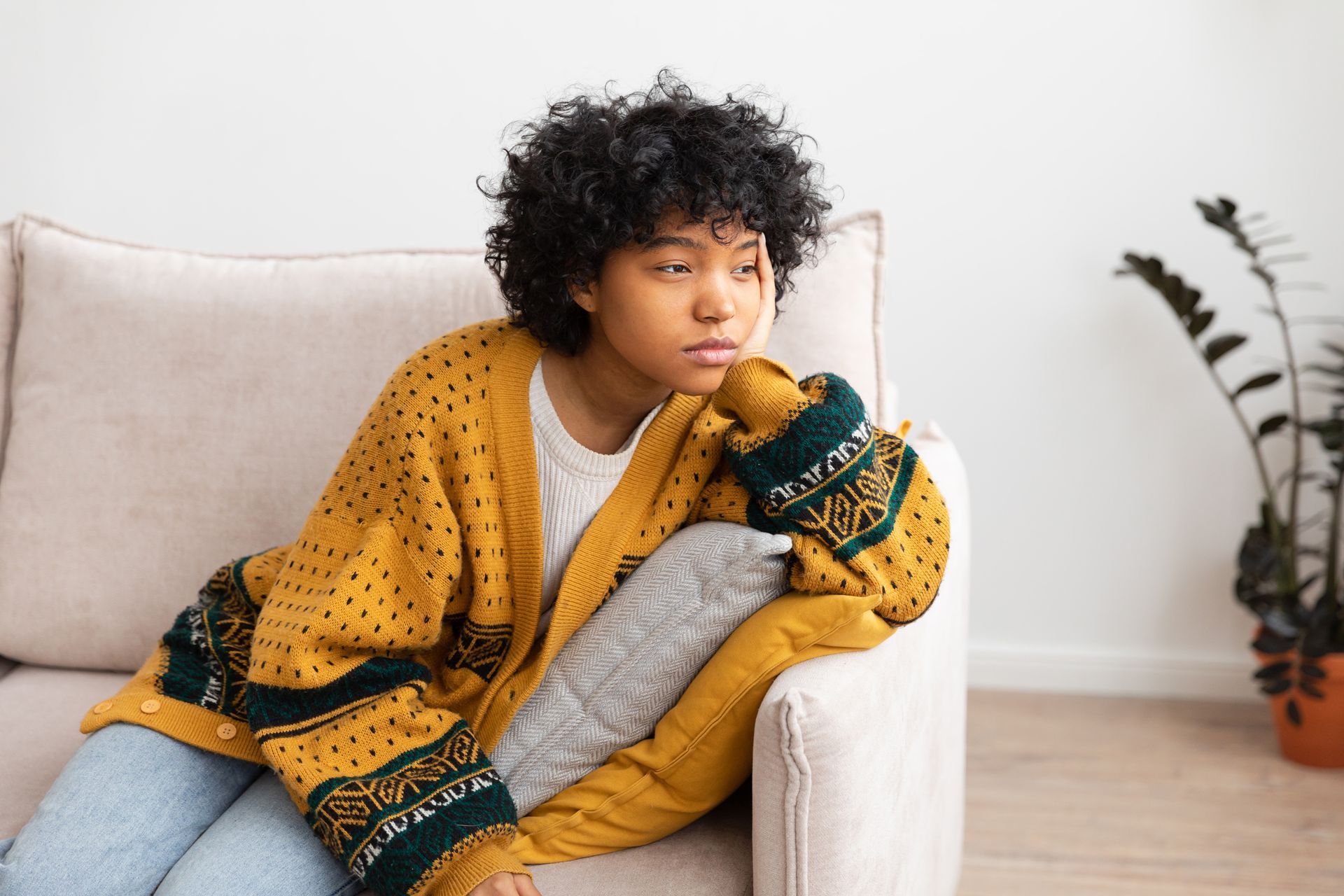 a person wearing a yellow cardigan sitting on a couch