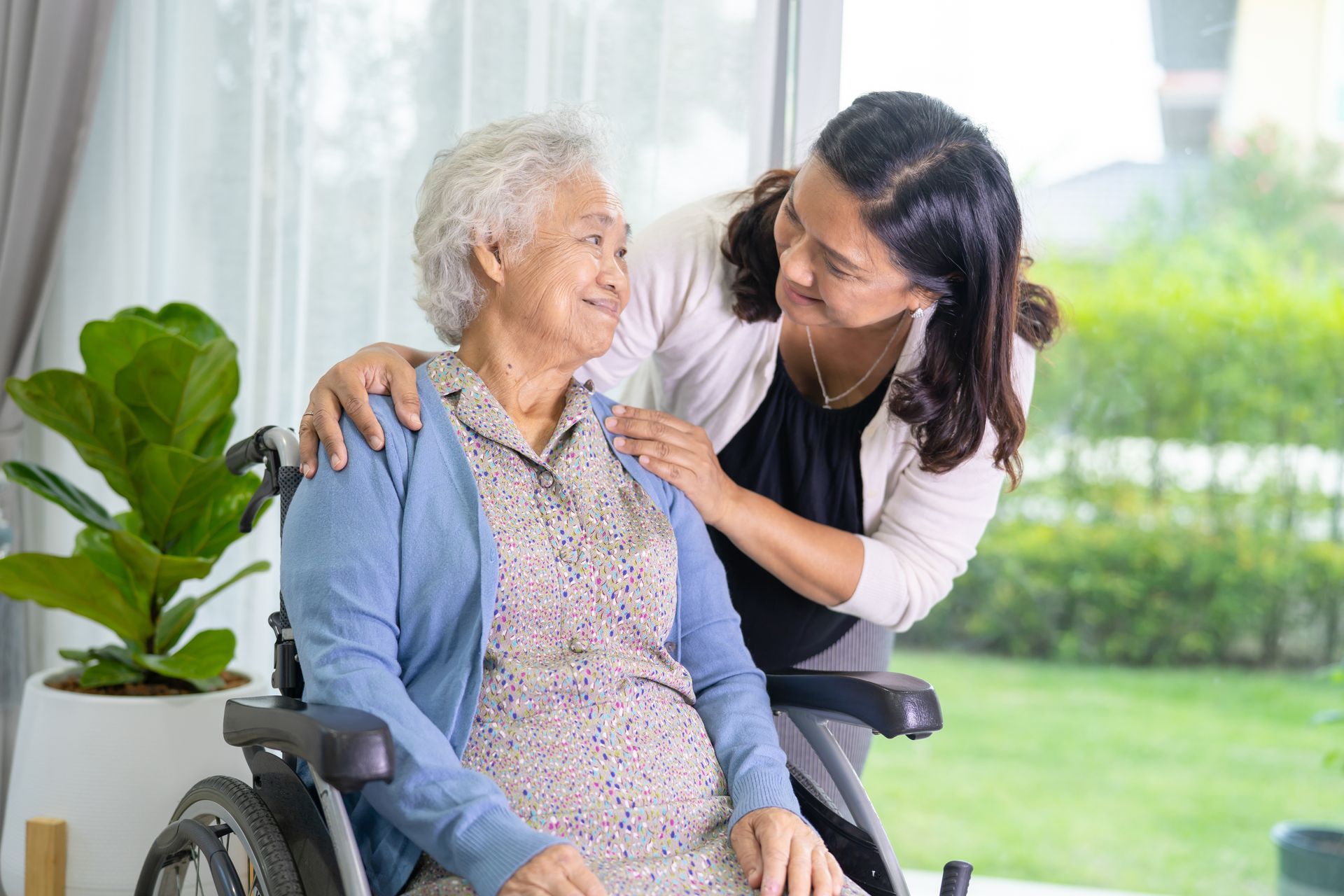 caretaker comforting an elderly woman in a wheelchair