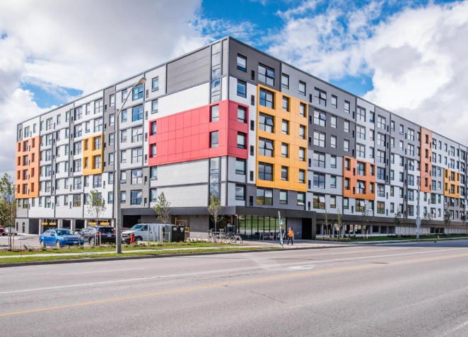 A large building with a lot of windows is sitting on the side of the road.