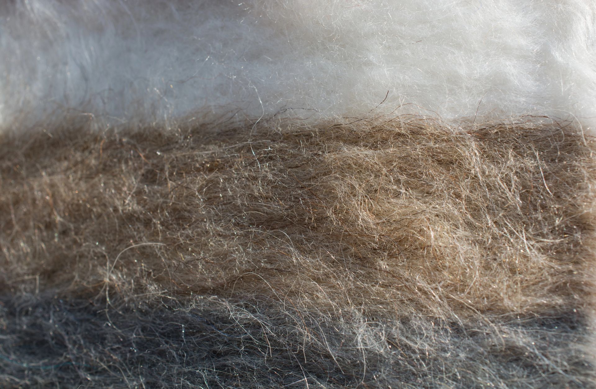 Strati di fibre di lana nelle tonalità del bianco, del marrone e del grigio.