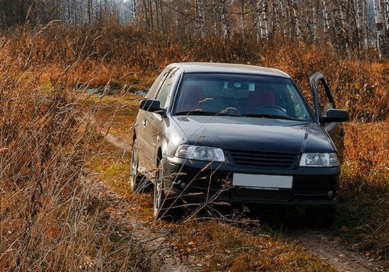 A Black car is Driving down a Dirt road in the Woods — Scrap Recyclers in Morisset, NSW