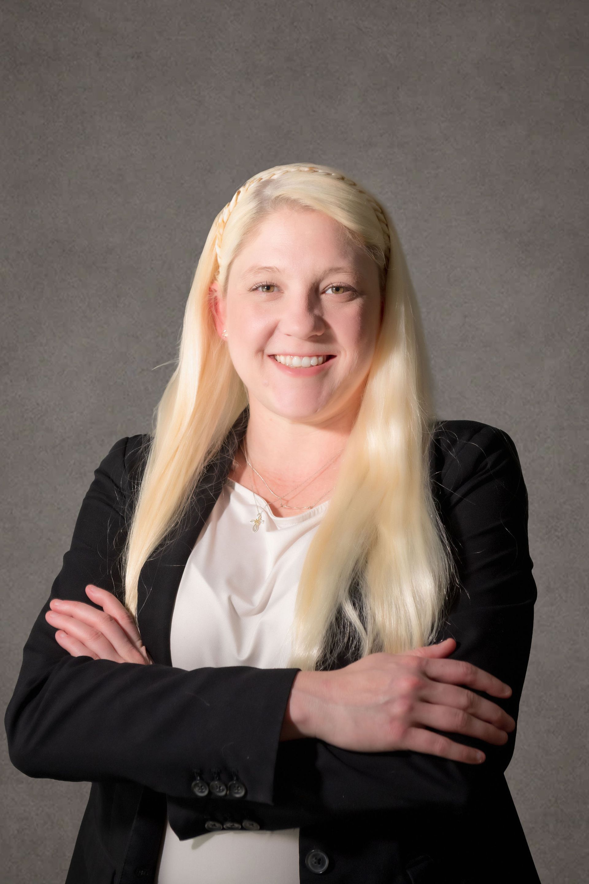 A professional headshot of Kristen Longmire, Associate Attorney, a woman wearing formal clothes in front of a grey background
