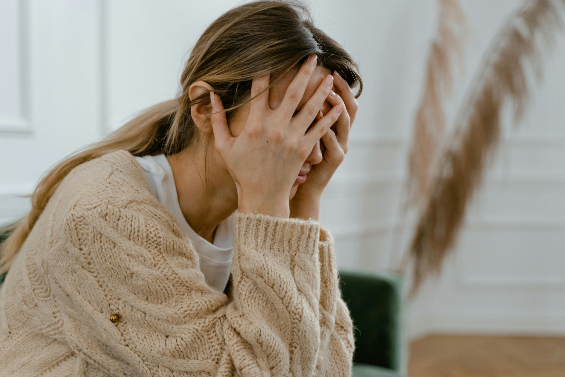 Woman with hands covering her face, looking distressed.