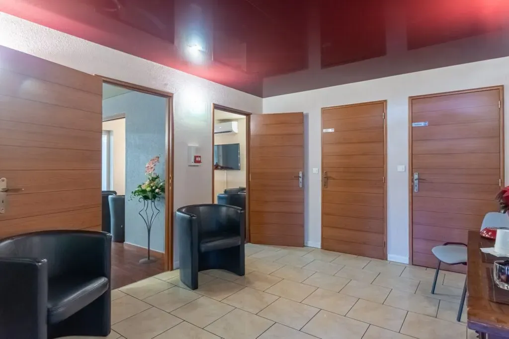 Une salle d'attente avec des chaises, une table et un plafond rouge.