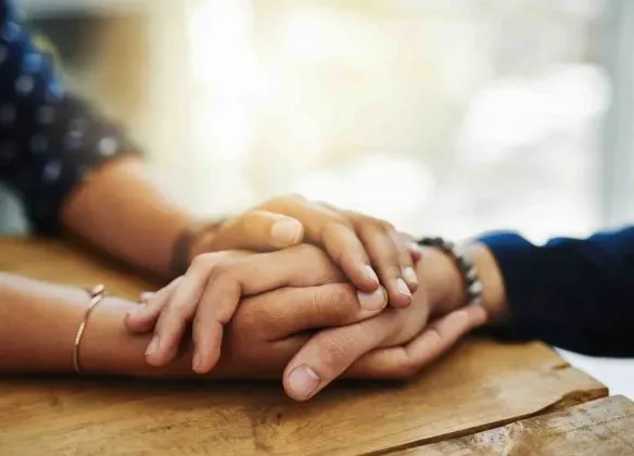 Un homme et une femme se tiennent la main sur une table en bois.