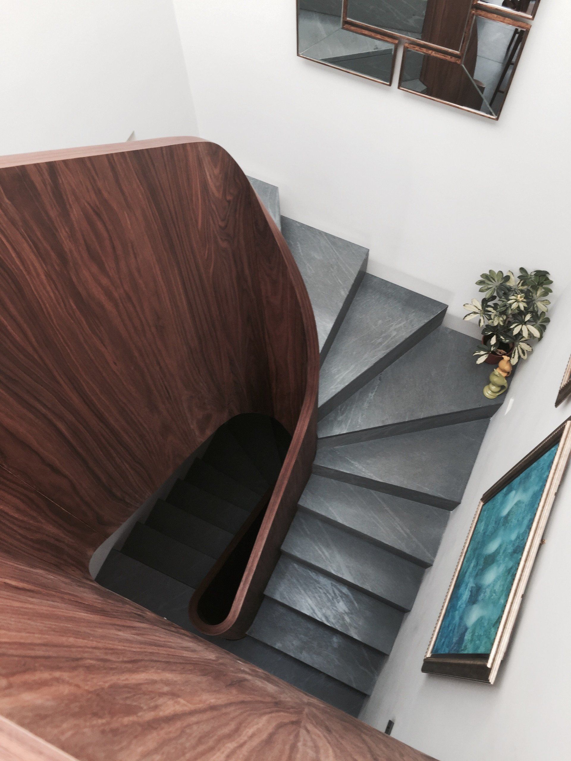 A spiral staircase with a wooden railing and a picture on the wall