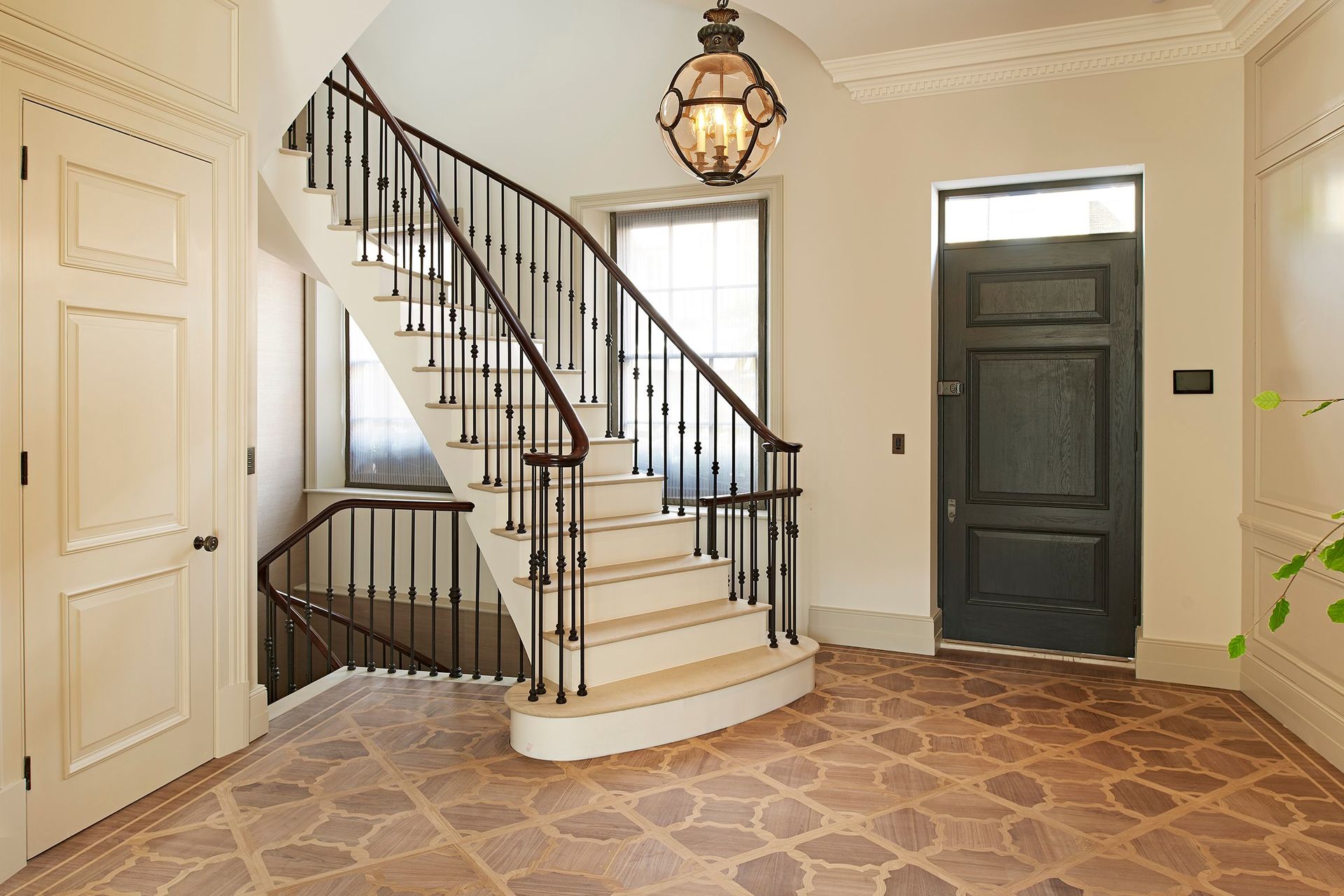 A hallway with a staircase and a black door