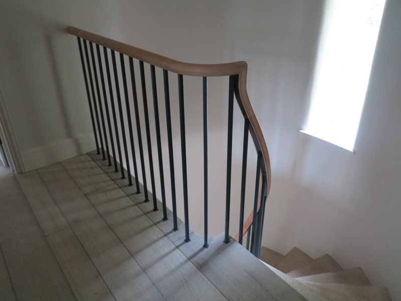 A staircase with a metal railing and a wooden handrail.