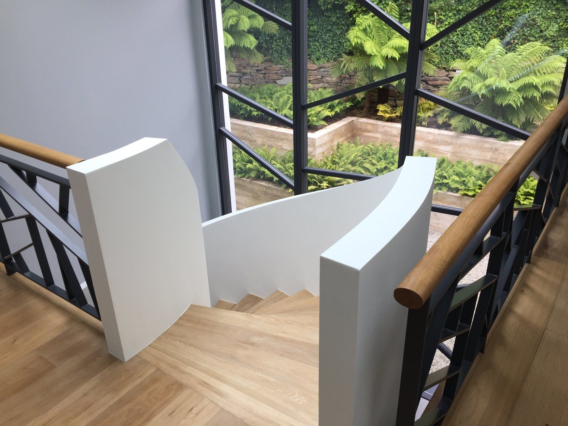 A staircase with a wooden railing and a large window