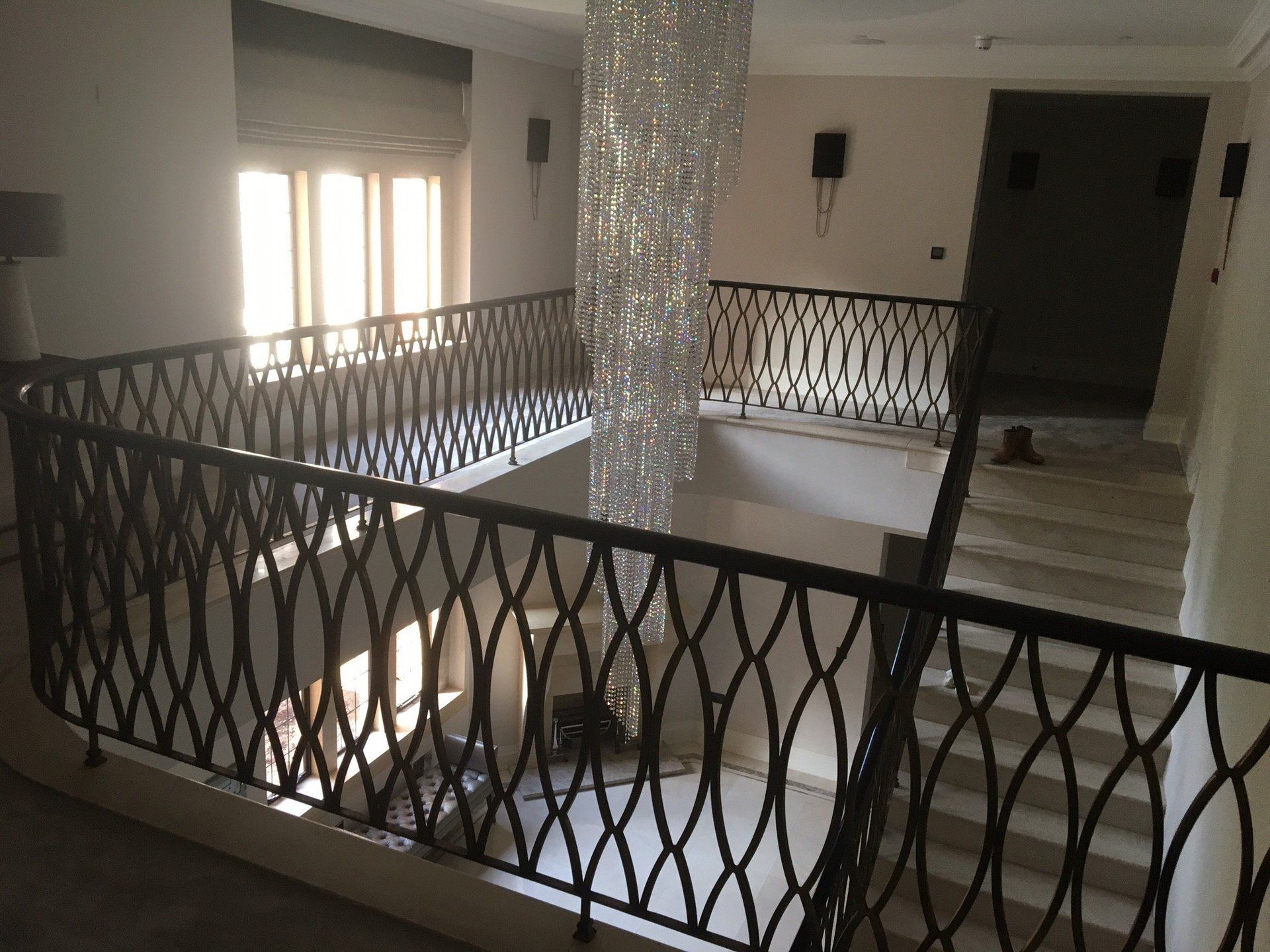 A staircase with a black railing and a chandelier in the background