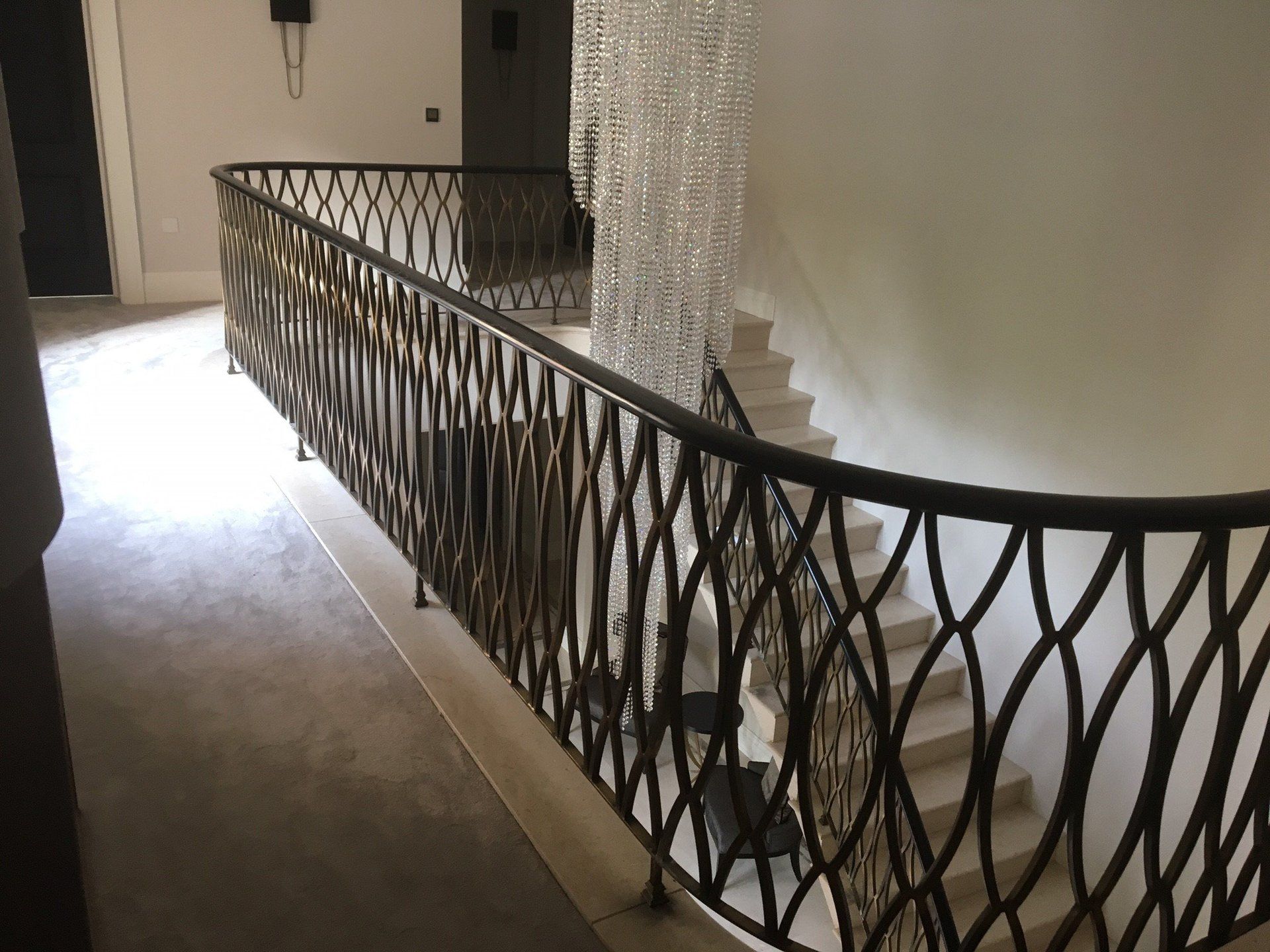 A staircase with a wrought iron railing and a chandelier hanging from the ceiling.
