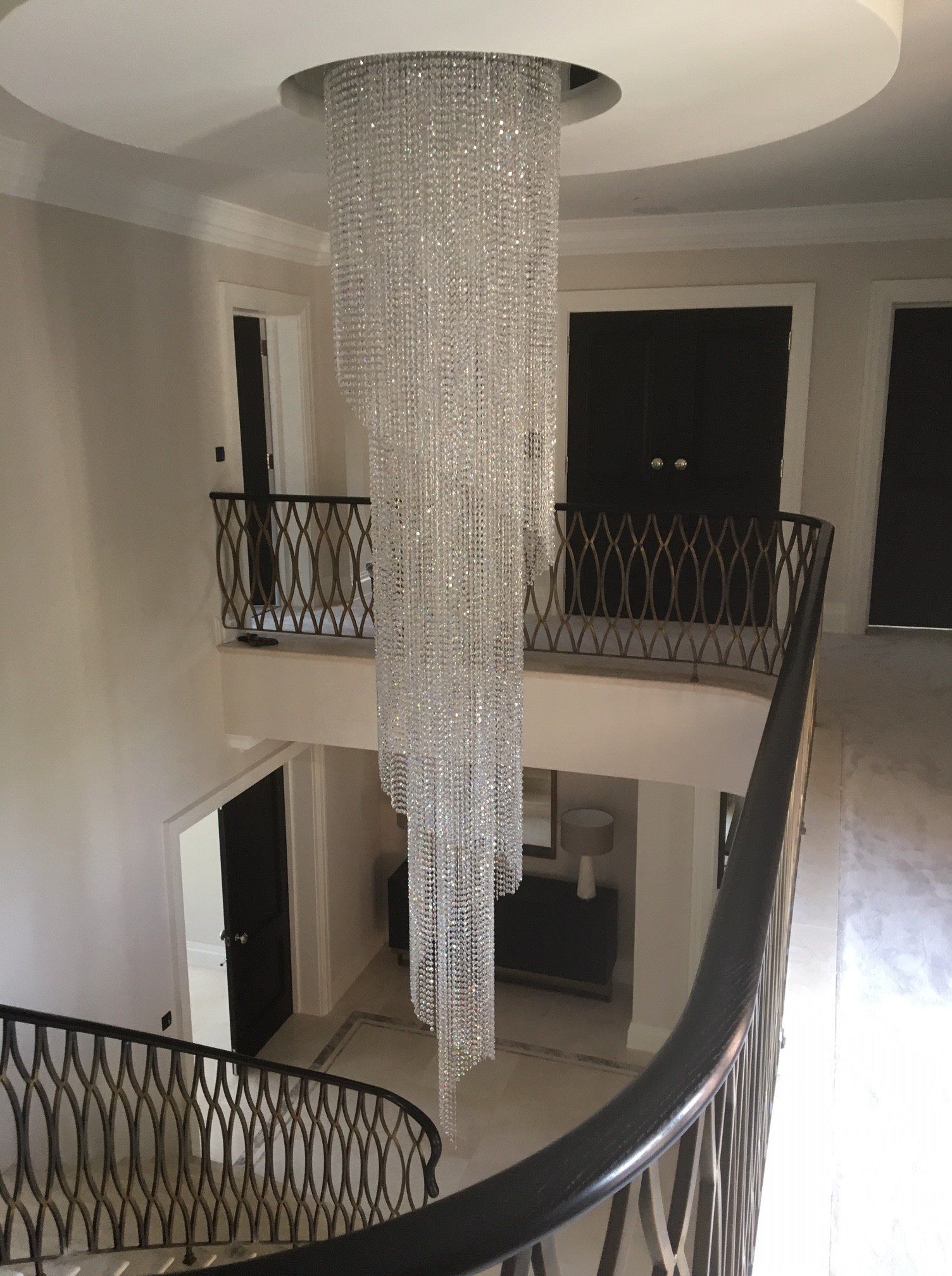 A large chandelier is hanging from the ceiling above a staircase.