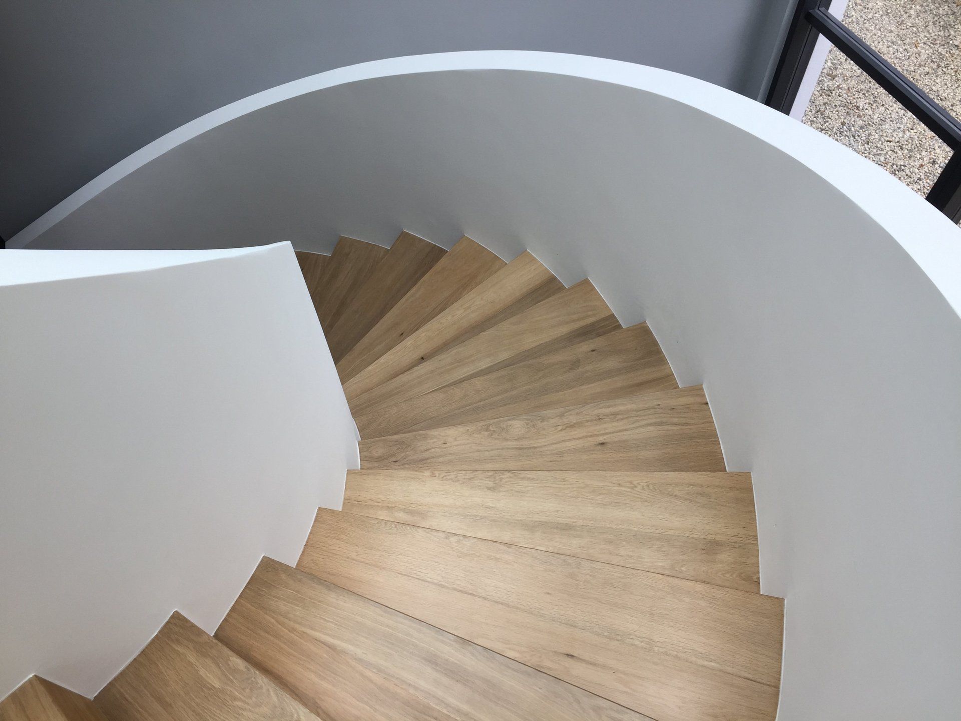 A spiral staircase with wooden steps and a white railing