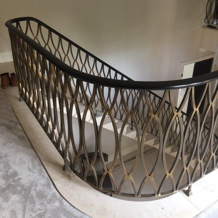 A staircase with a wrought iron railing and a wooden handrail