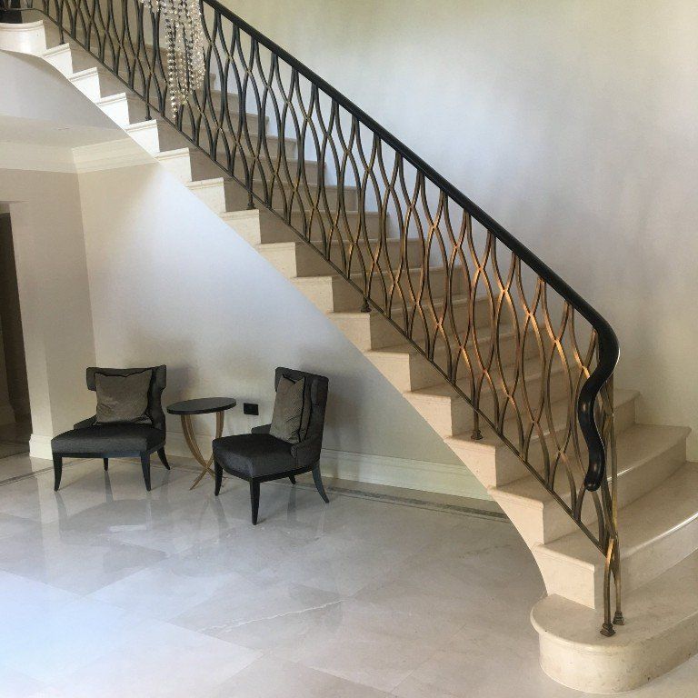 A staircase with a wrought iron railing and chairs