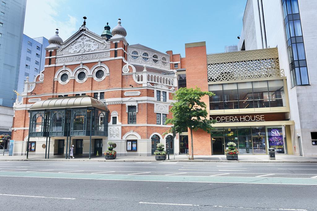 A large brick building is sitting on the corner of a city street.