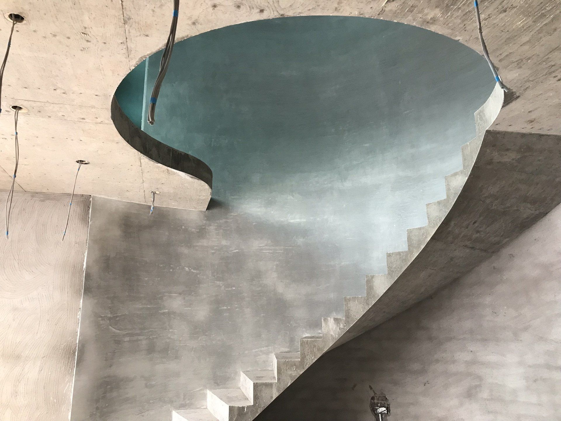 A spiral staircase with a hole in the ceiling.