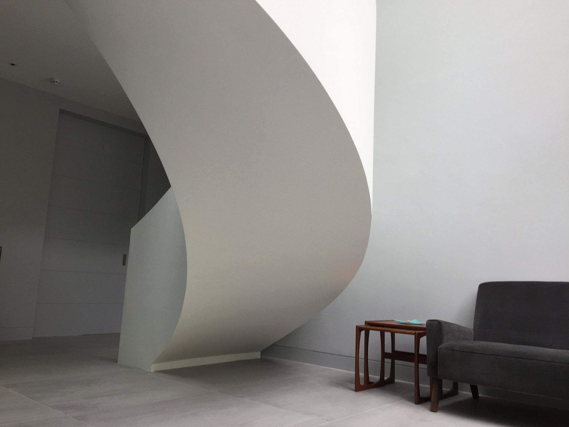 A living room with a couch a table and a spiral staircase