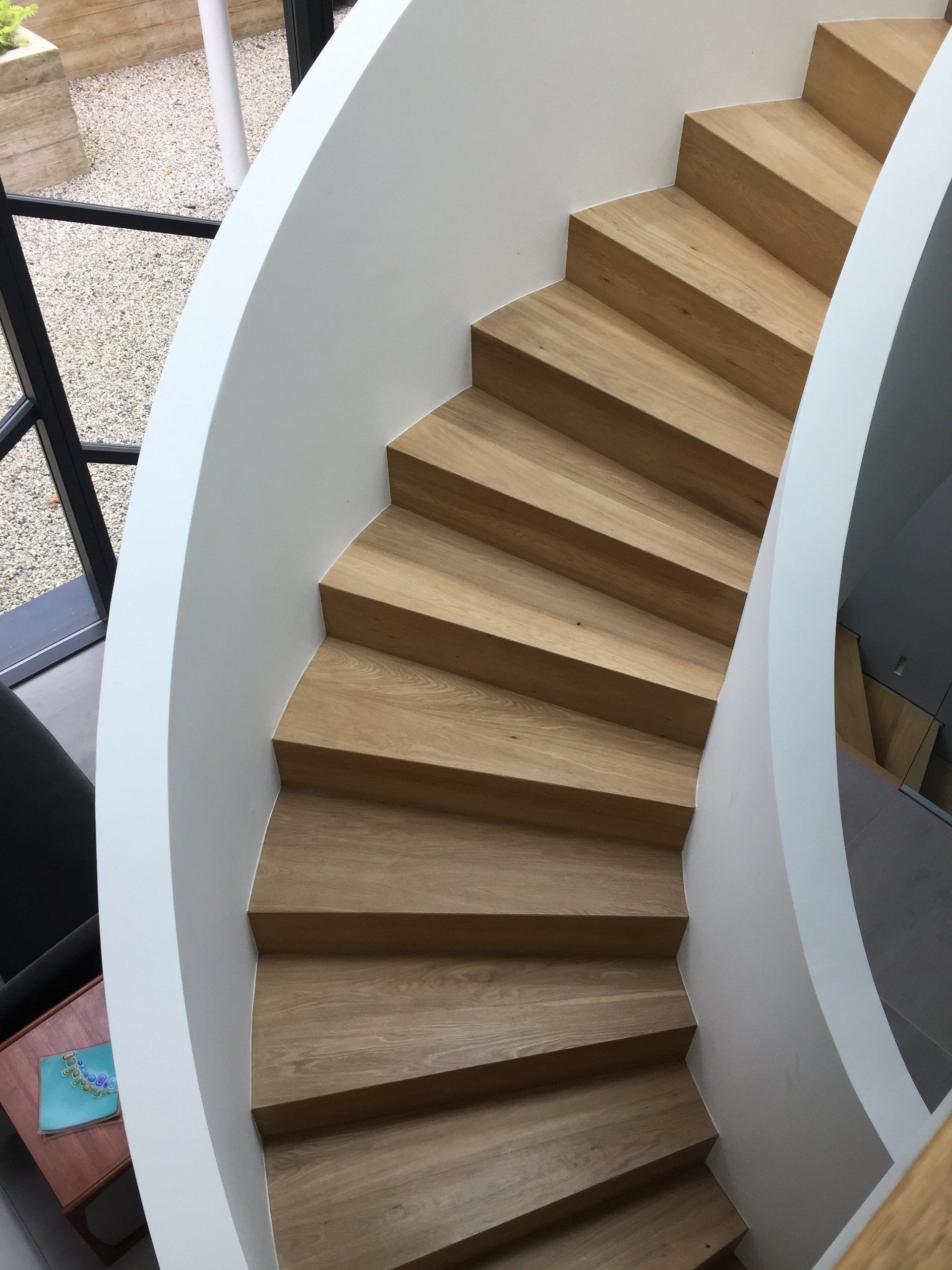 A spiral staircase with wooden steps and a white railing