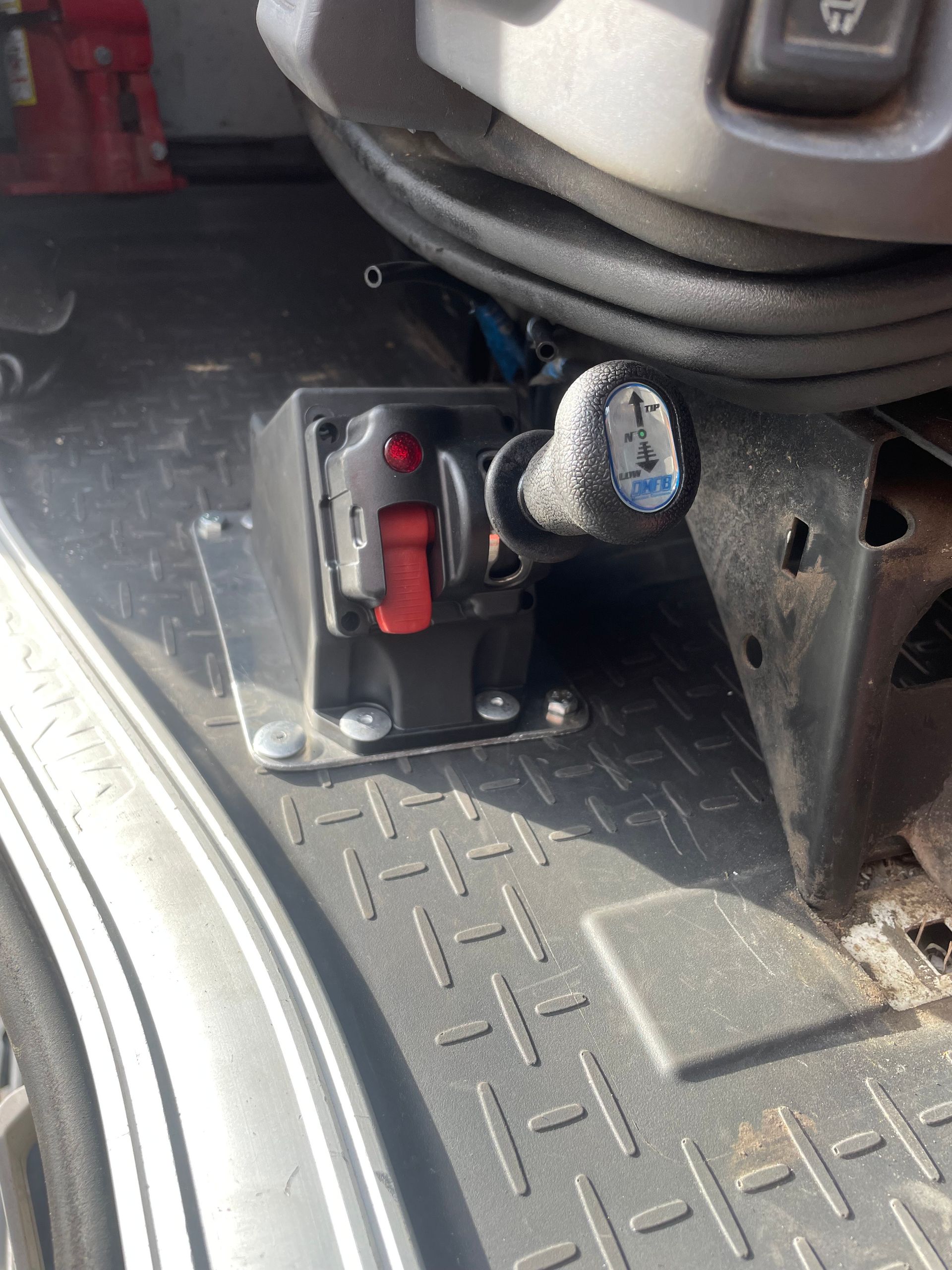 Black and gray truck interior. Red button, gear shift, and metal flooring with diamond pattern.