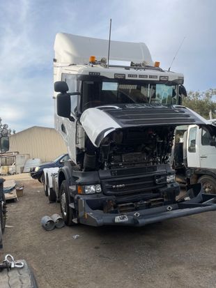 White semi-truck with hood open, parked outside.