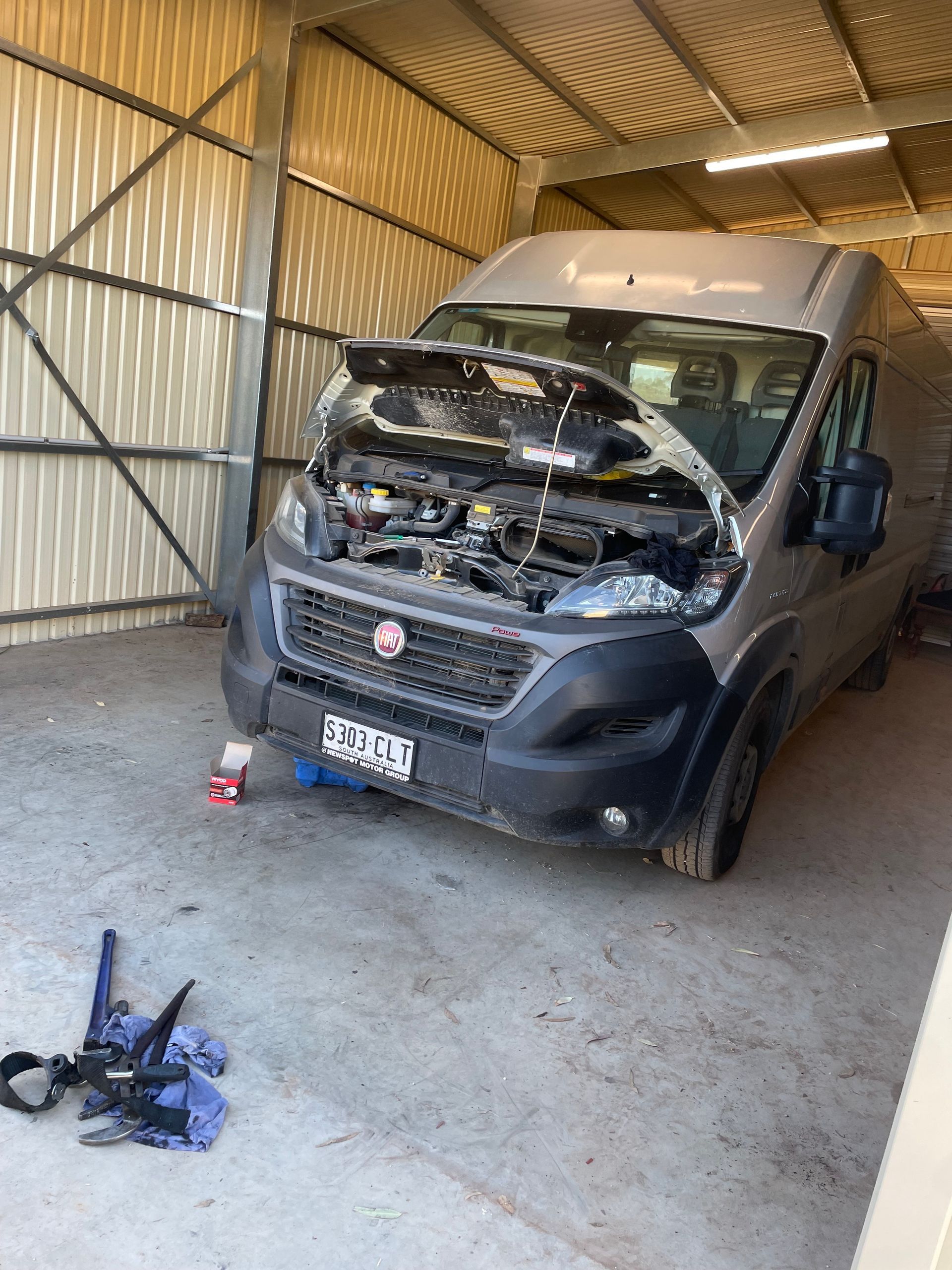 Van with open hood in a garage; mechanic work in progress.