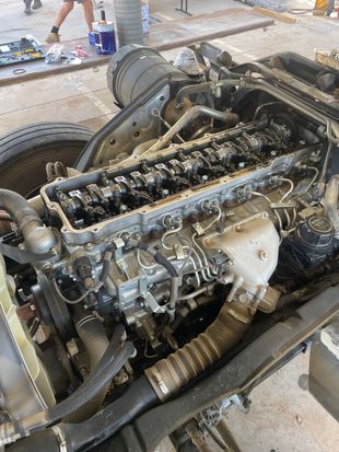 Diesel engine removed from truck chassis, showing various components and hoses.