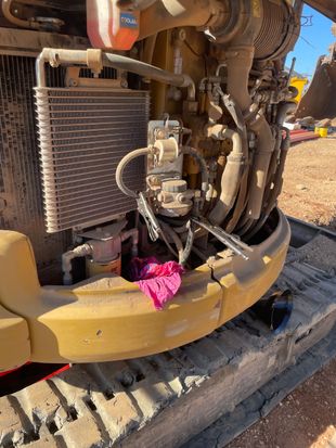 Yellow construction equipment engine with a radiator and a pink cloth hanging.