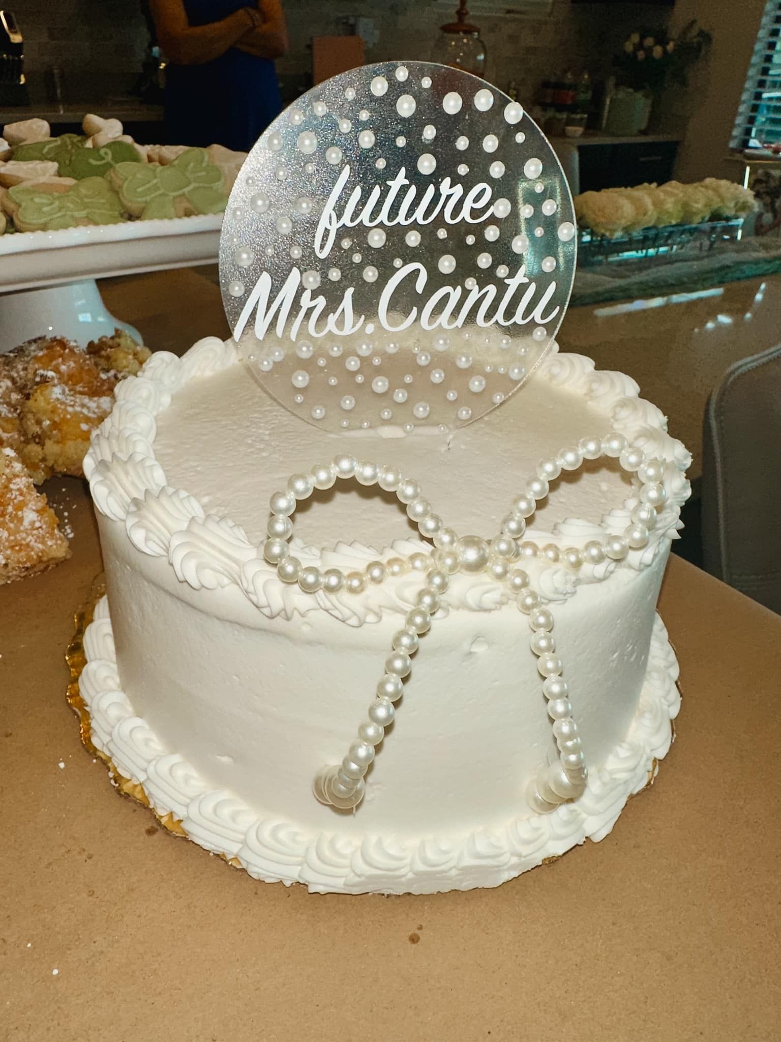 A white cake with pearls and a bow on top of it.