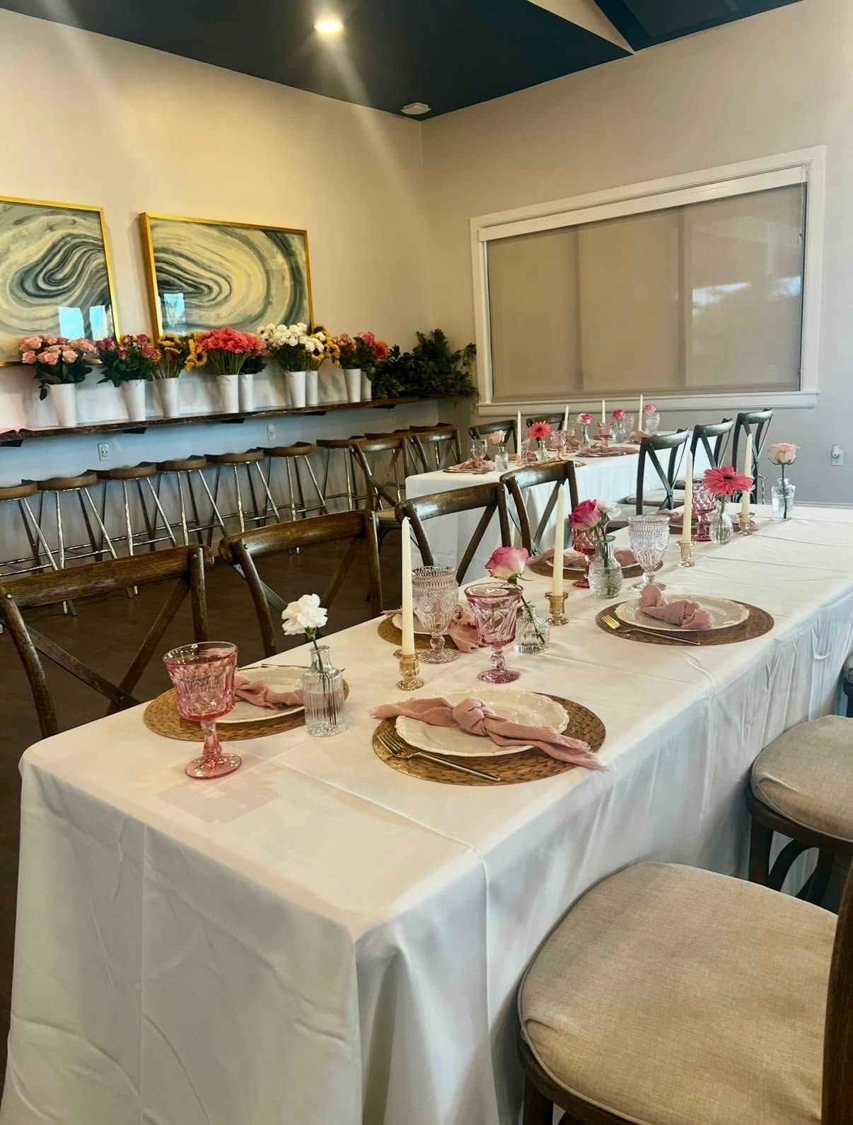 A long table with plates , candles , and flowers on it in a room.