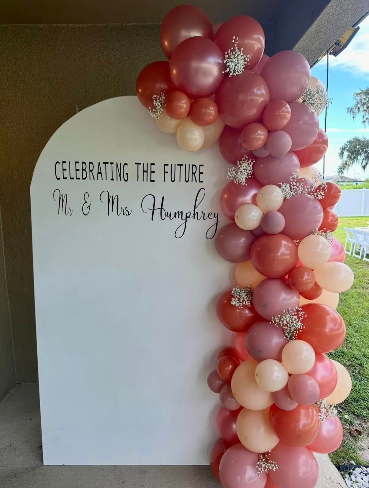 A sign that says celebrating the future is surrounded by balloons.