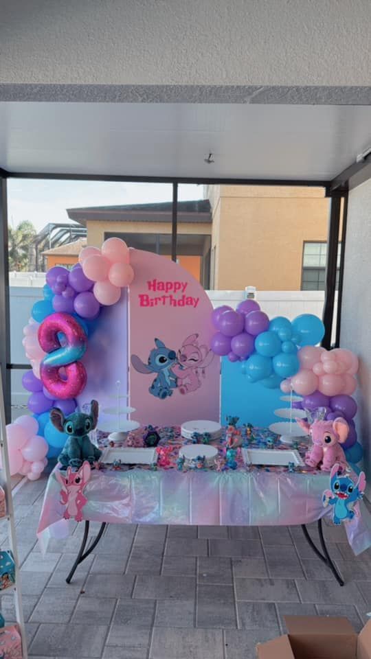 A table decorated with balloons and stuffed animals for a birthday party.
